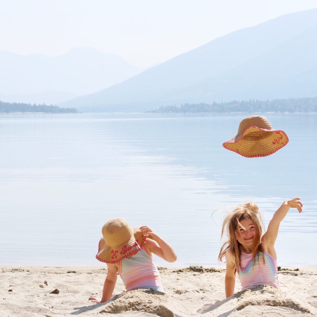 a little girl throws her hat on the beach