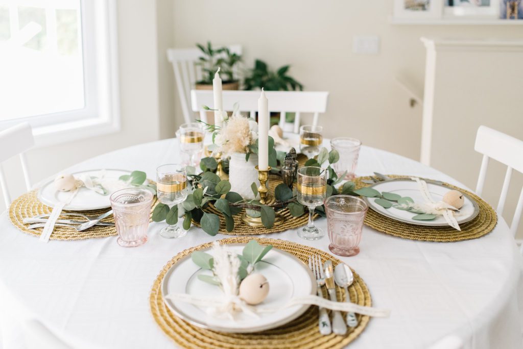A dining table with greenery and gold accents