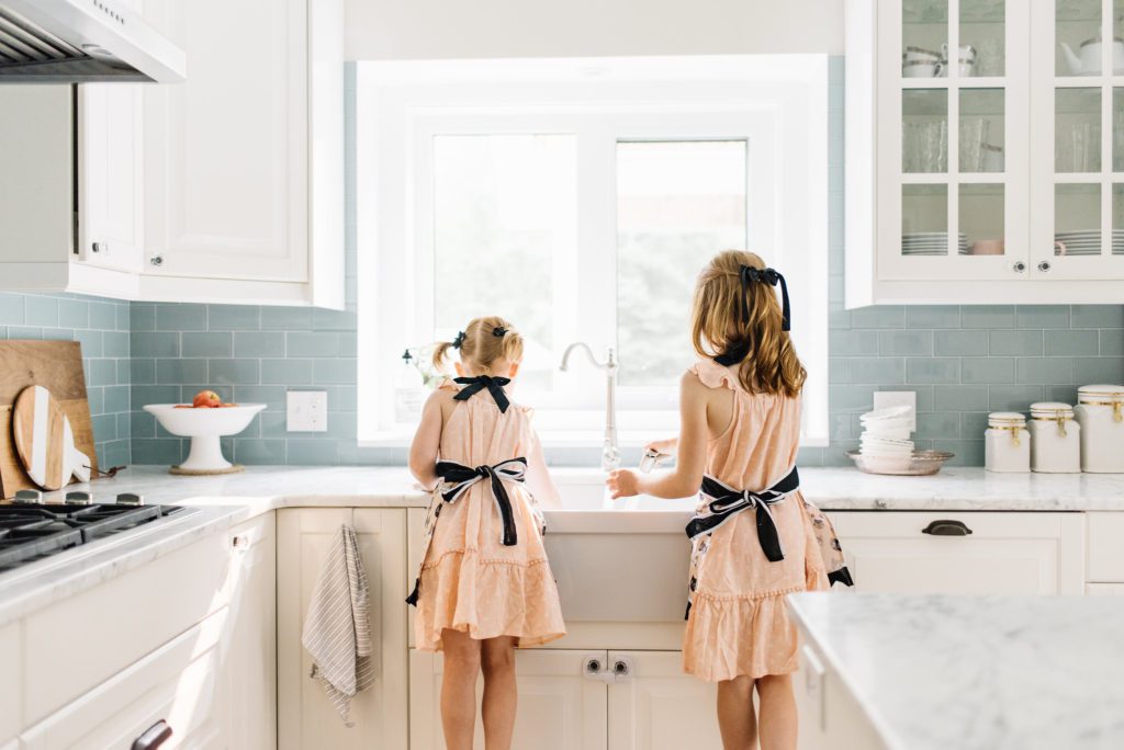2 girls do dishes wearing aprons