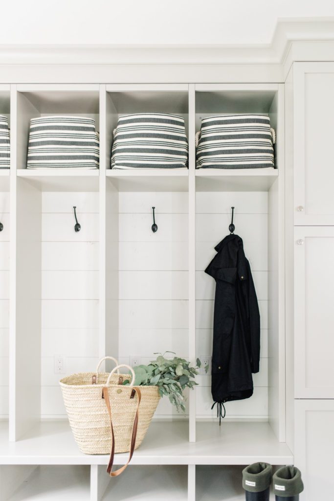 Open lockers with coat hooks and storage bins allow for quick access in this mudroom design