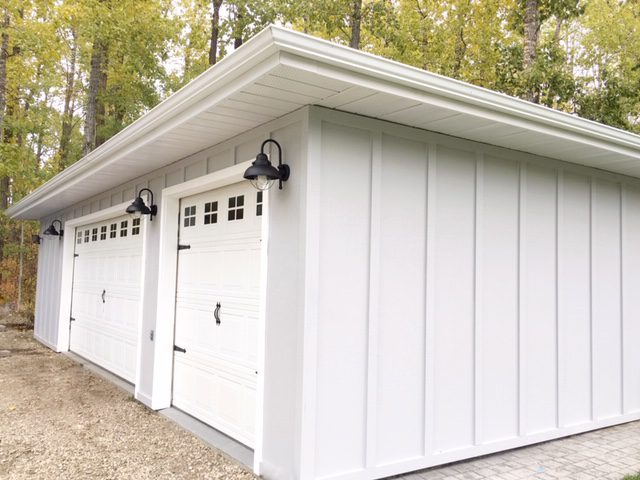 Grey board and batten siding and black gooseneck lights add modern farmhouse appeal to the detached garage.