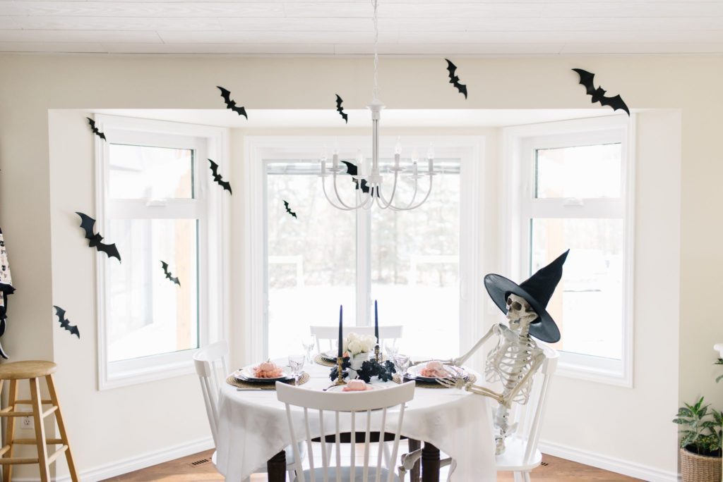 A skeleton has a seat at a Halloween tablescape