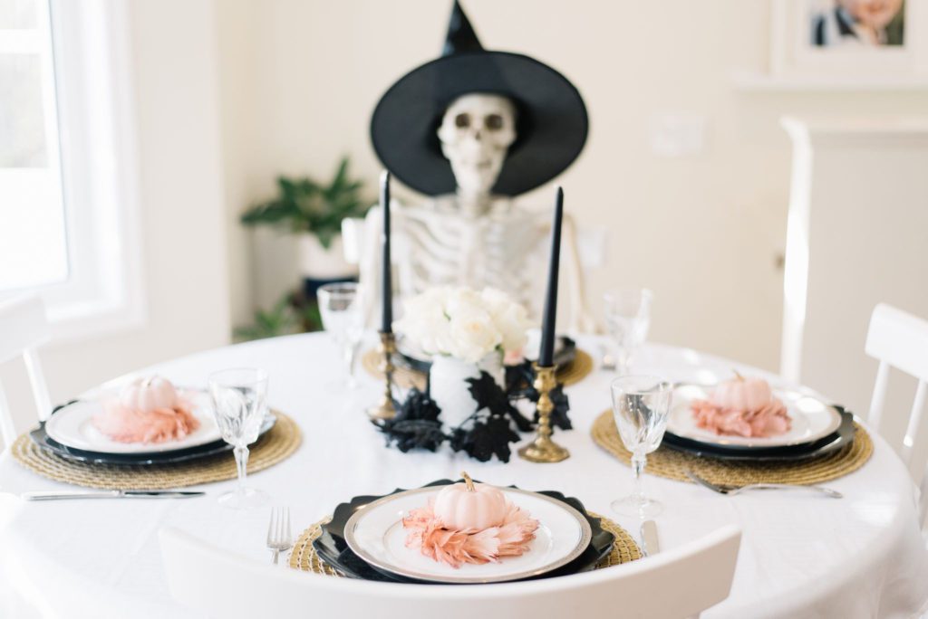 skeleton sits at a halloween tablescape with black candles