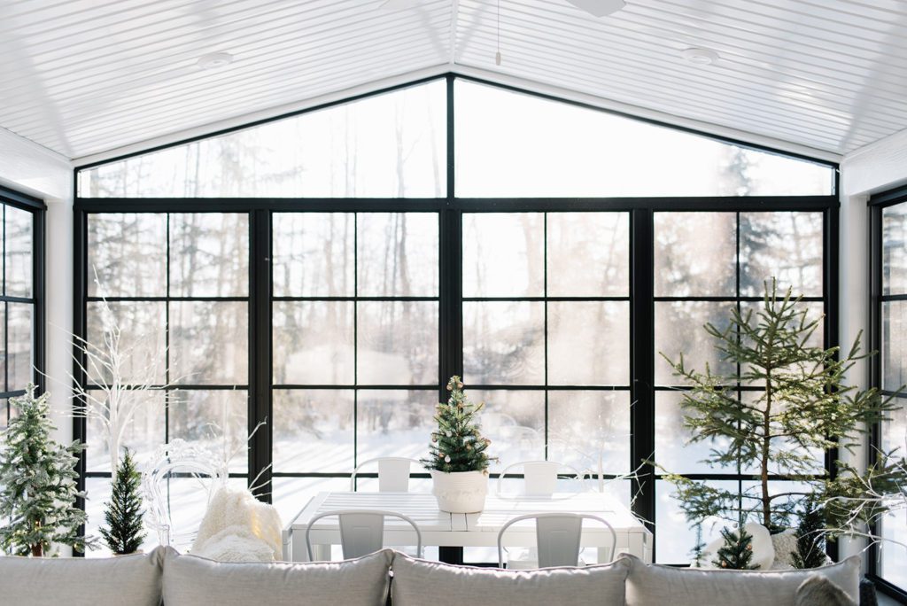 A sunroom with large windows looking out to a snowy back yard
