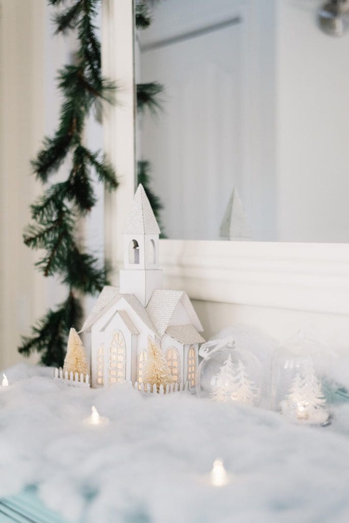 A lit winter village vignette in faux snow