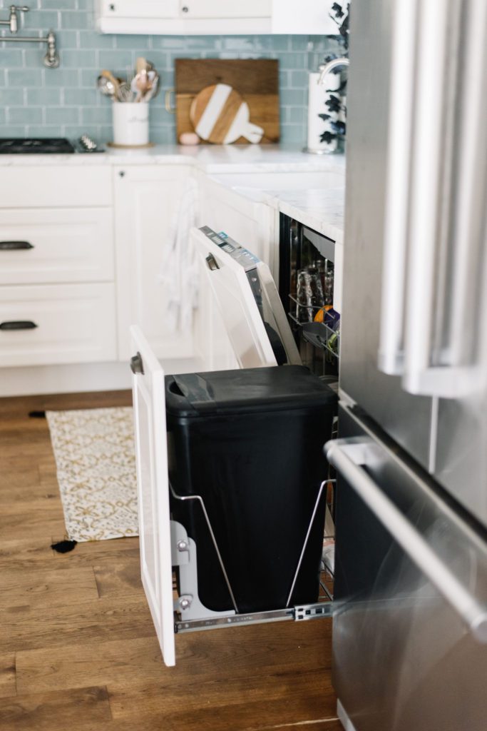 open dishwasher and garbage pullout in kitchen