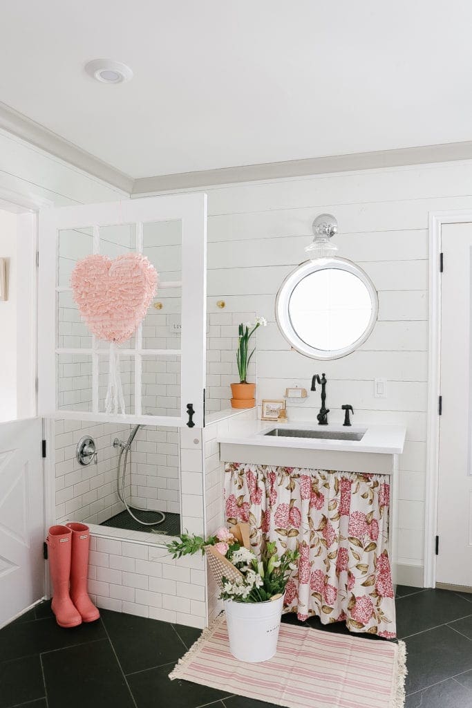 Farmhouse mudroom decorated for Valentines day with a heart pinata and pink hunter boots