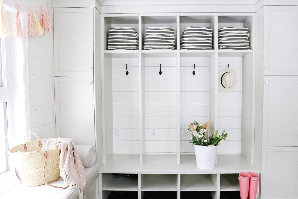 mudroom with striped baskets and a large bucket of flowers