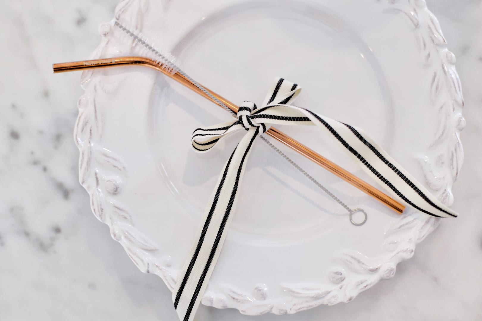 straw and brush tied with ribbon on plate