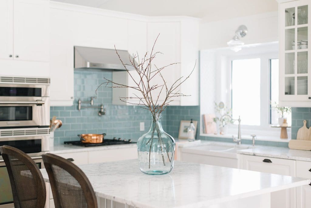 A large blue glass vase filled with branches on a kitchen island