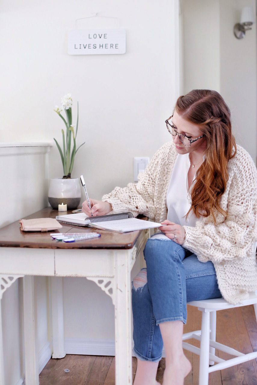 woman sitting at a desk writing in a paper planner