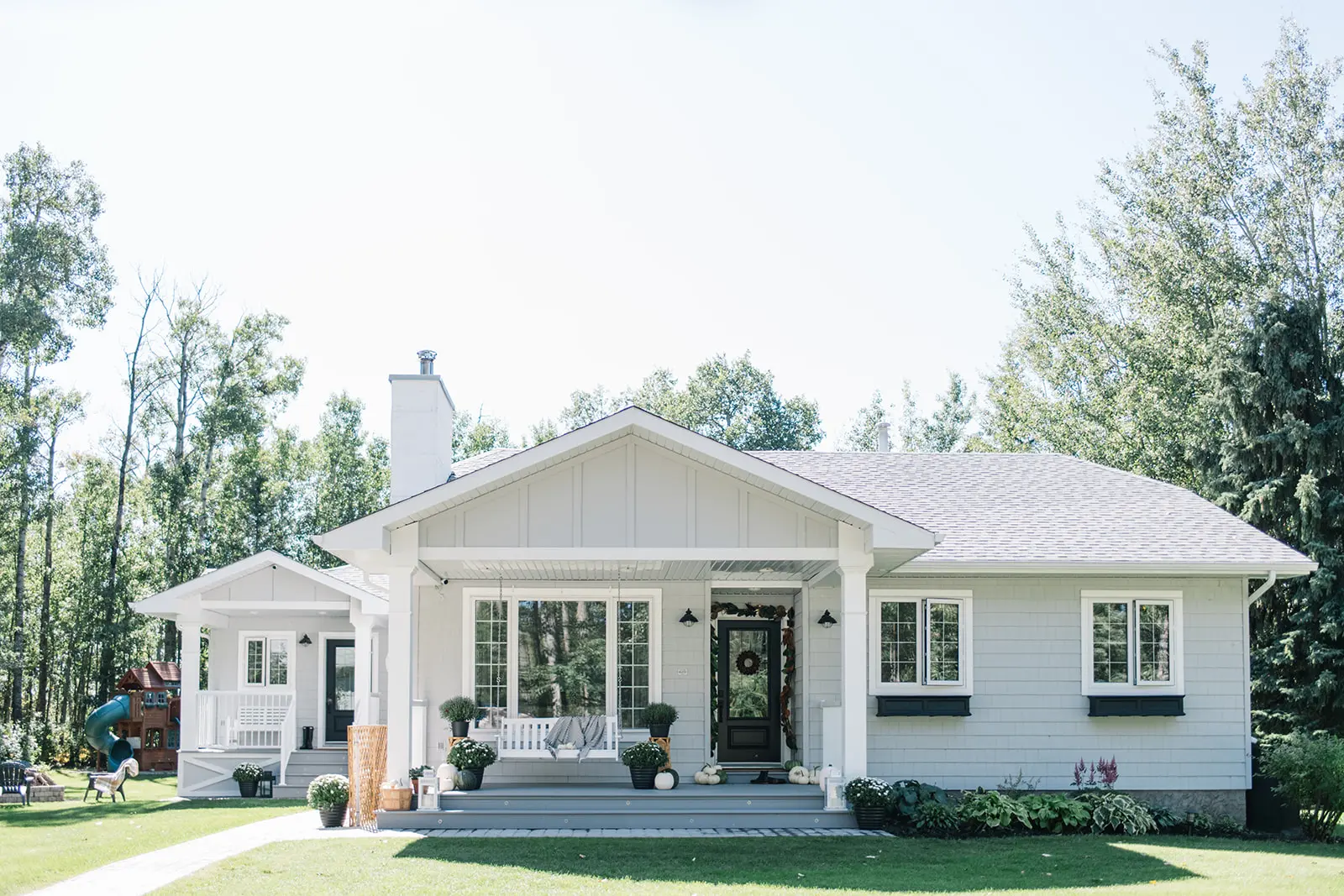 A modern farmhouse style exterior renovation created this single level home with grey siding, a black door and white windows