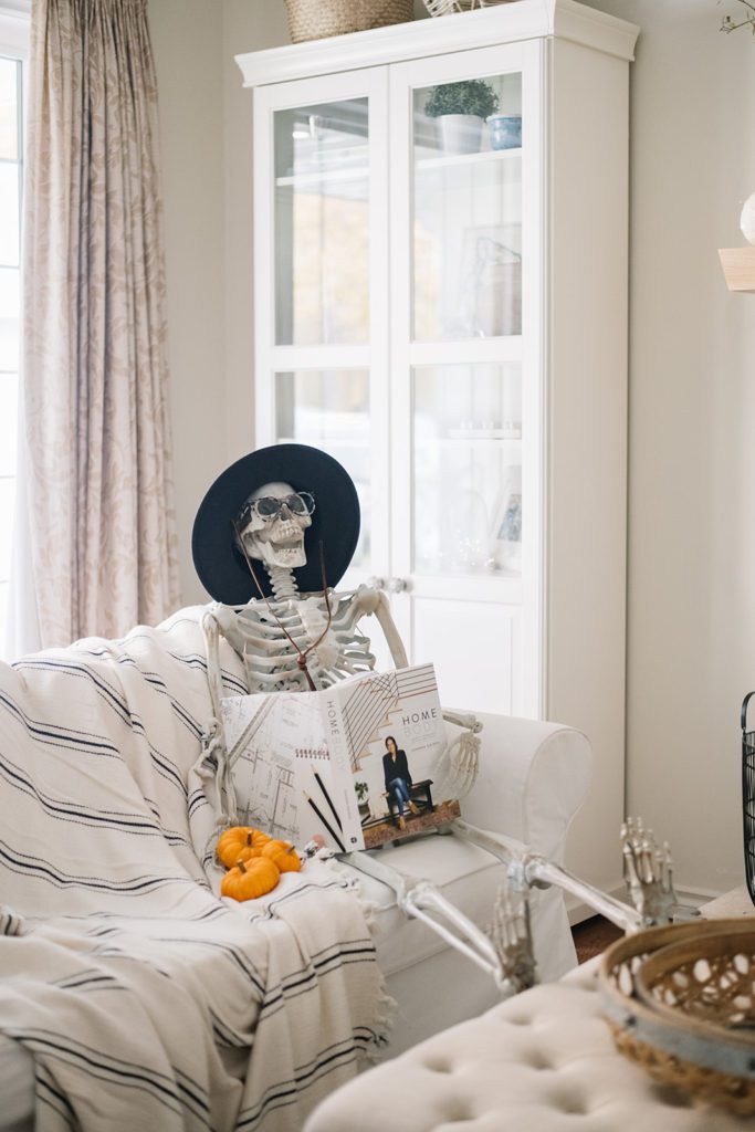 halloween skeleton sits on a couch reading a book