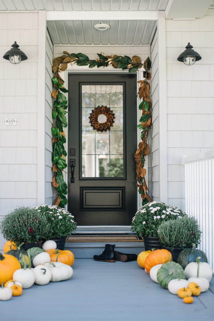 front door decorated for fall with magnolia garland and pinecone wreath