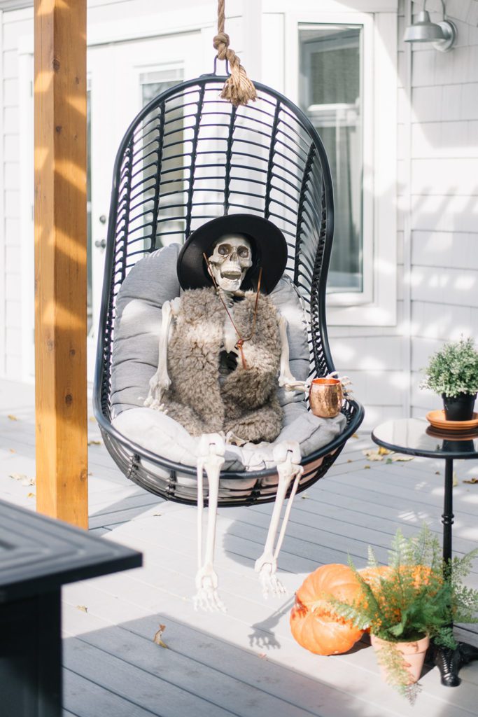 Halloween skeleton decoration sitting in an outdoor swing