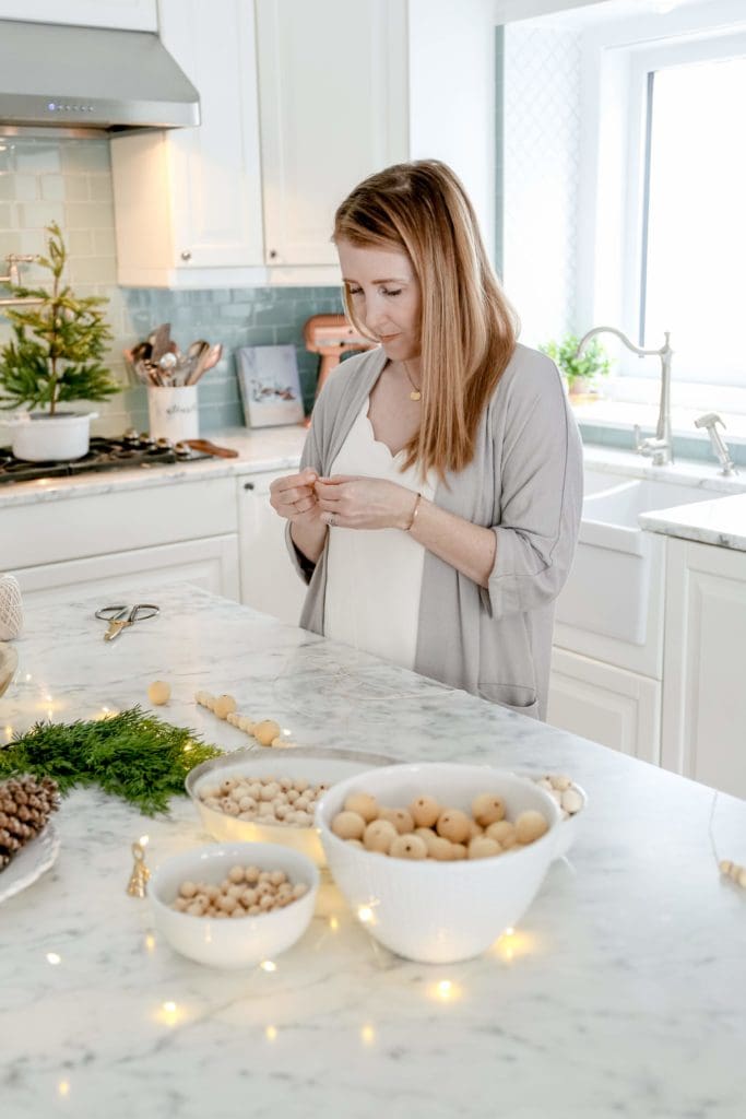 A woman making a garland out of wooden beads