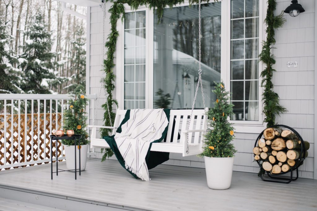 A minimal front porch with fresh Scandi style for Christmas. Fresh holiday greenery hung over the window