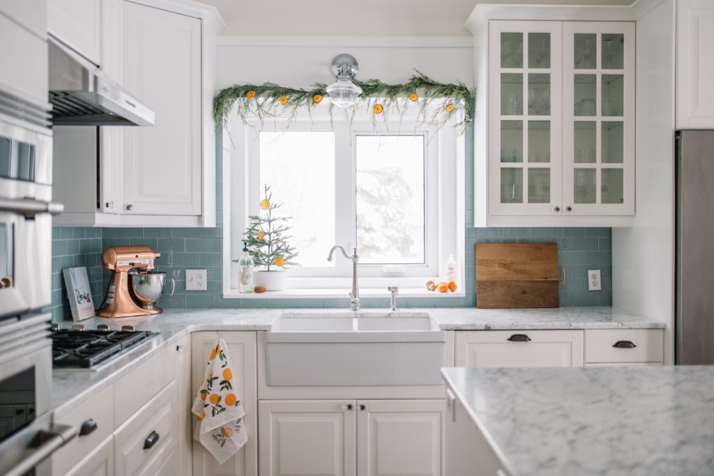 Farmhouse Kitchen with dried orange and faux cedar garland hung over the kitchen window
