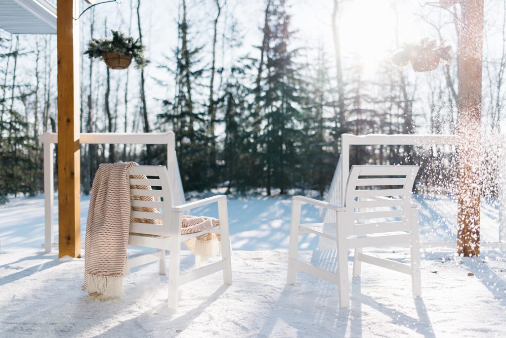 2 chairs facing a snowy backyard draped with blankets