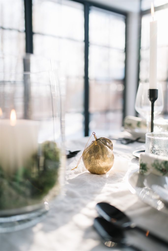 a brass pear ornament sits on a christmas table