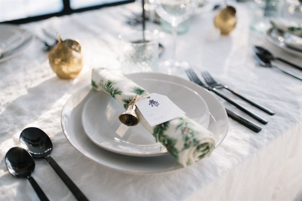 christmas place setting with name tags and brass bells tied to the napkins