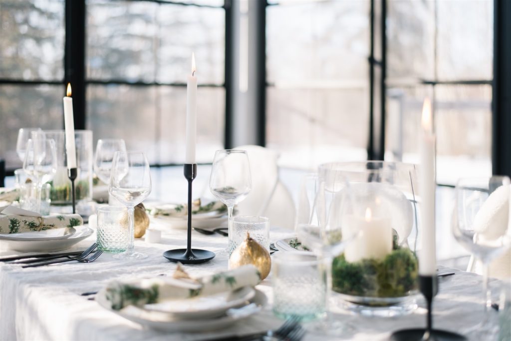 A modern and minimal country Christmas table setting with black candle holders and gold pear ornaments