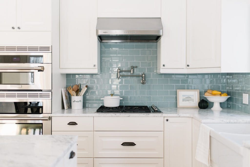 White kitchen with gas stovetop and stainless steel range hood