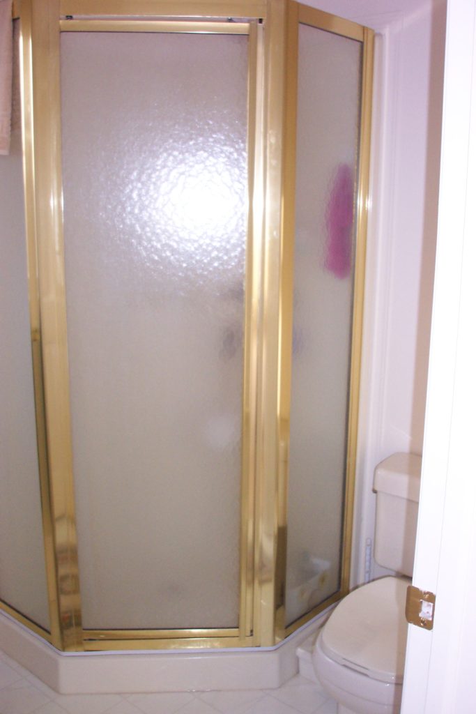 Outdated 90s bathroom with gold glass shower