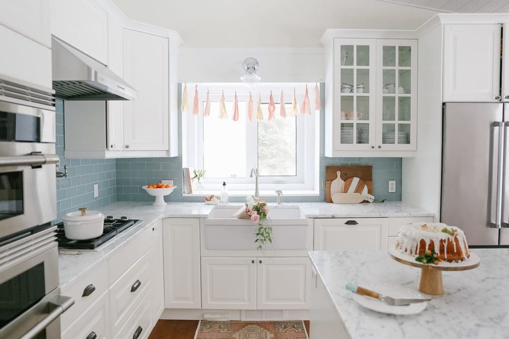 A kitchen with a sink and a window decorated with a banner and flowers