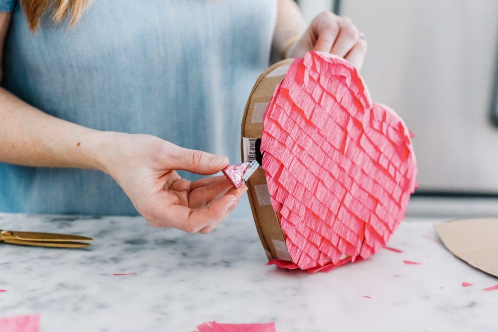 putting candy into a heart pinata