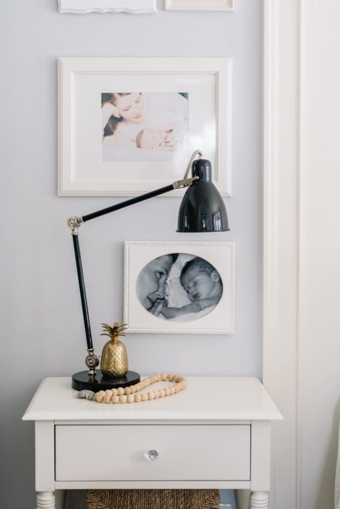 A black industrial style lamp acts a a bedside light on a white farmhouse style side table in a master bedroom.