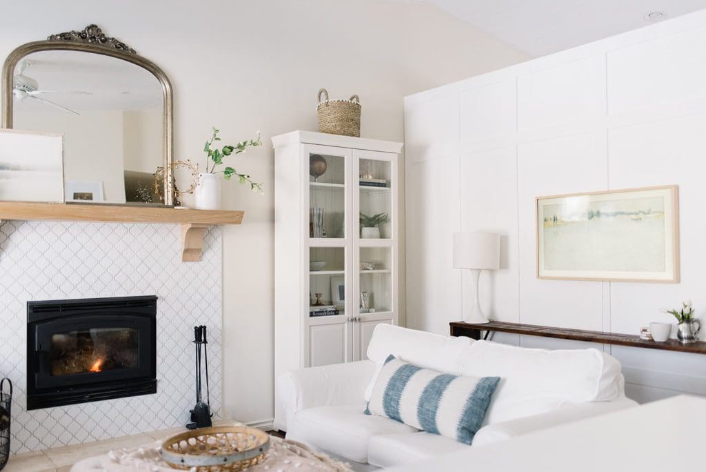 A living room white couches and bookshelves and blue striped pillows