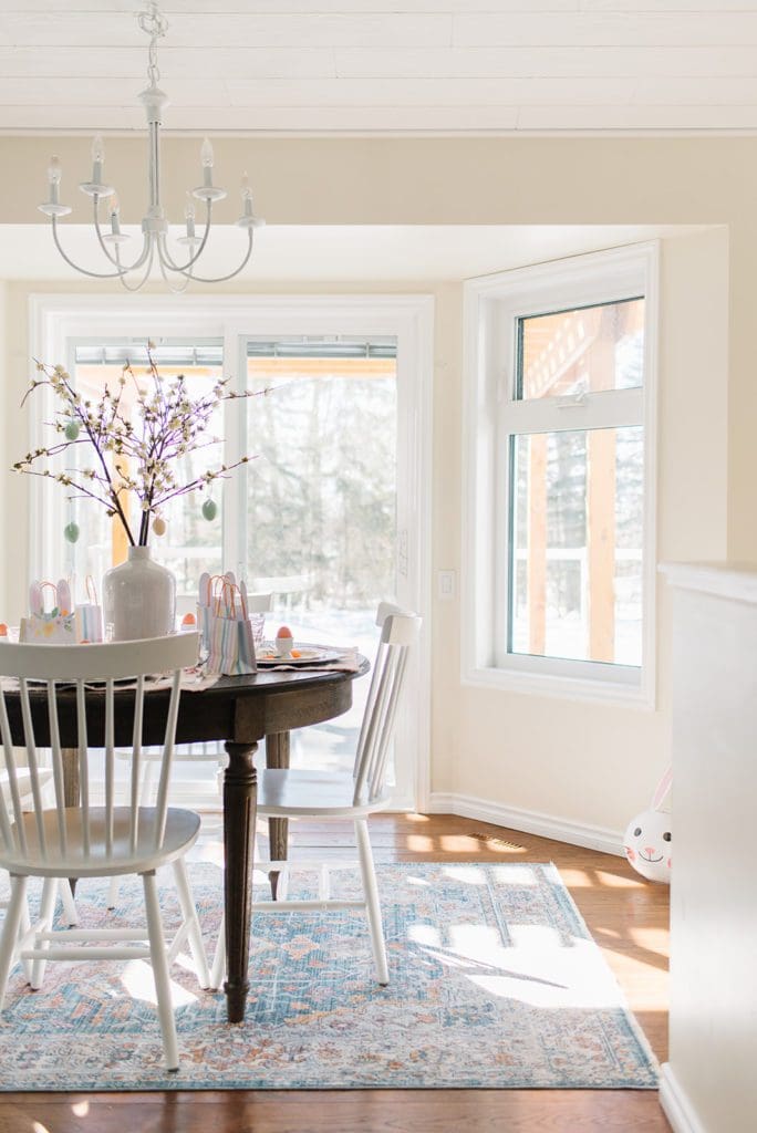 A dining room table  set up as kids easter tablescape in front of a window