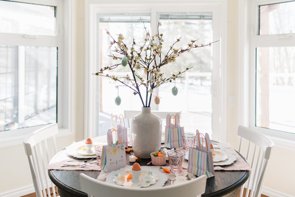 A kids easter tablescape set up with an Easter tree made from pussy willows and hanging Easter eggs