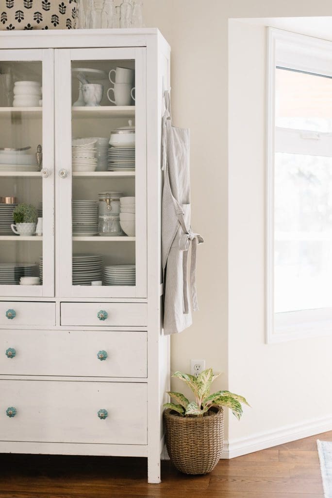 A dining room hutch with an apron hanging on the side