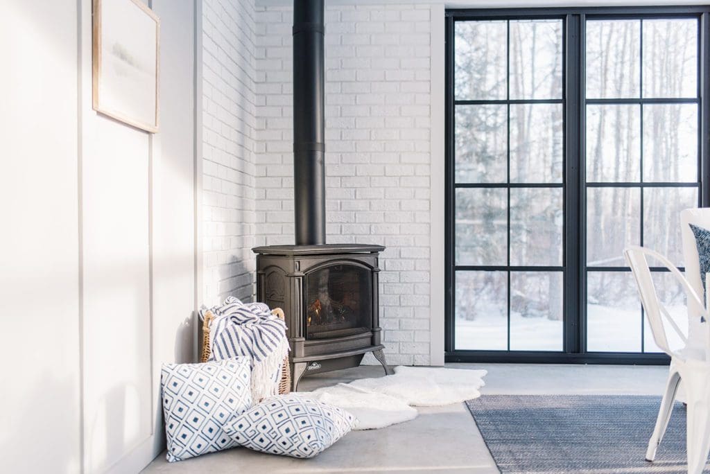 A stove next to floor to ceiling black windows