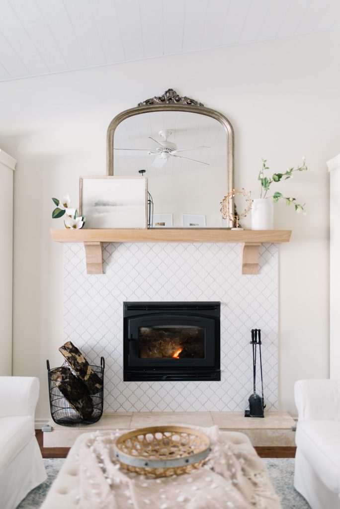 fireplace with white tile and white oak mantle with gold mirror