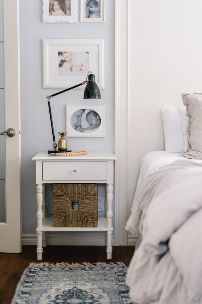 white side table beside bed with black lamp and wicker basket