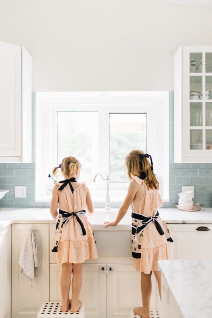 girls at the kitchen sink wearing aprons