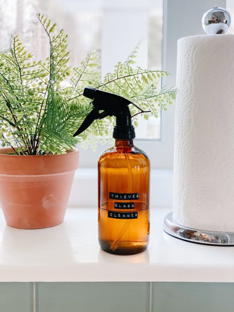 An amber bottle filled with homemade cleaner sits on a window ledge