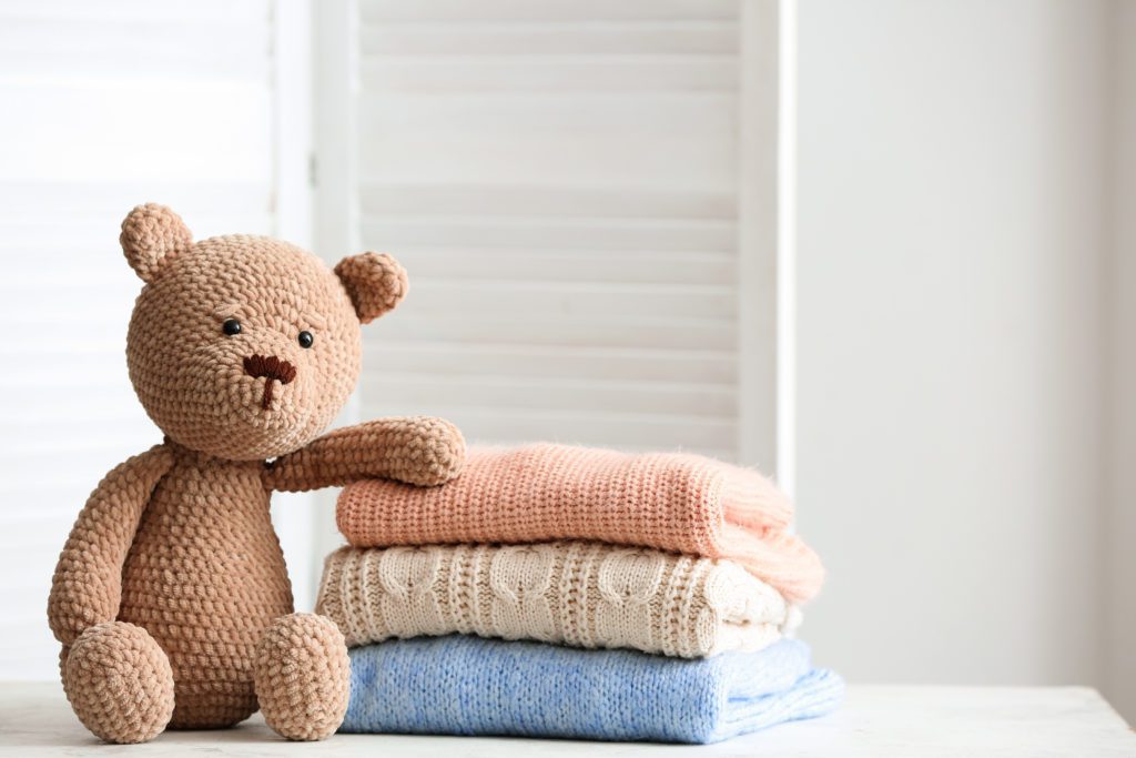 stack of sweaters next to a teddy bear