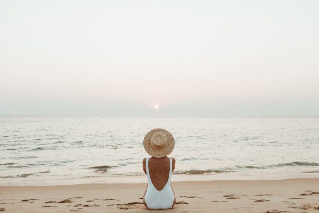 woman sitting on the beach staring out over the ocean