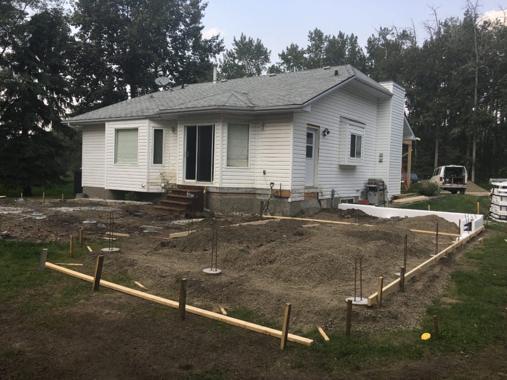 Small white house with markers set out for an addition