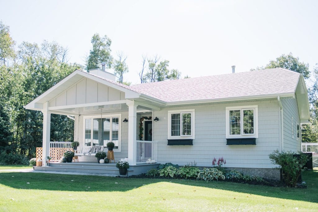 small farmhouse with grey siding and white windows