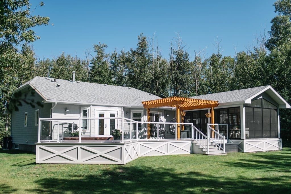 A large lawn in front of a house with a big deck