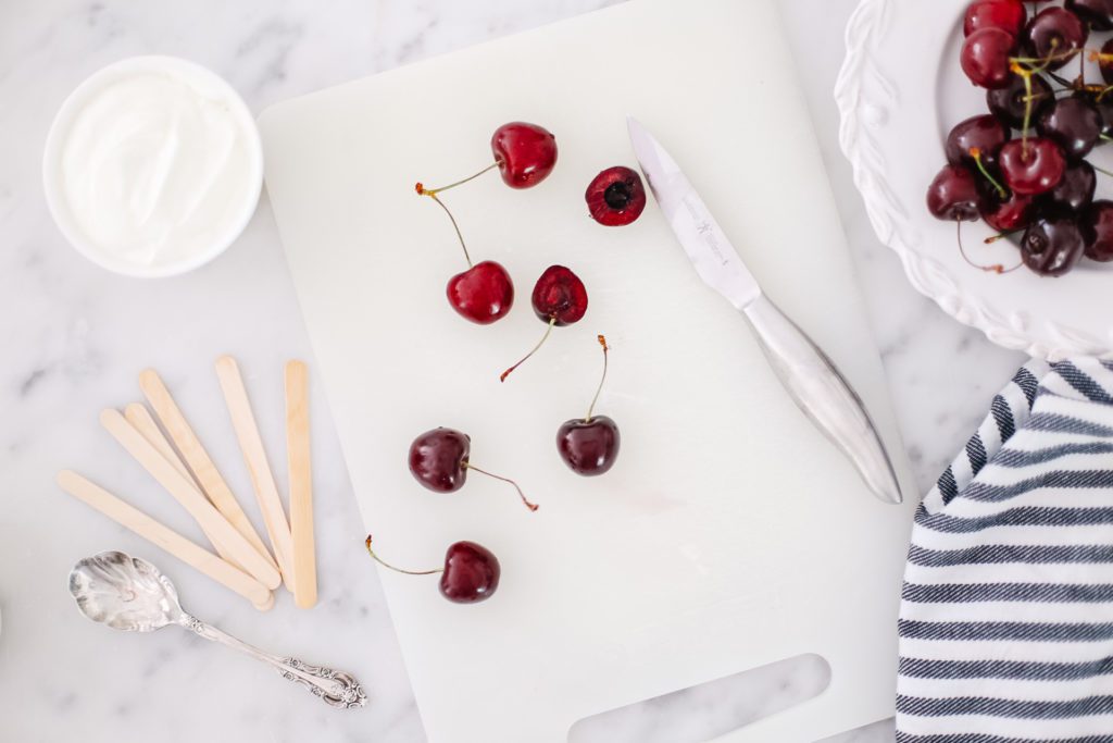 A cutting board with cherries and a knife