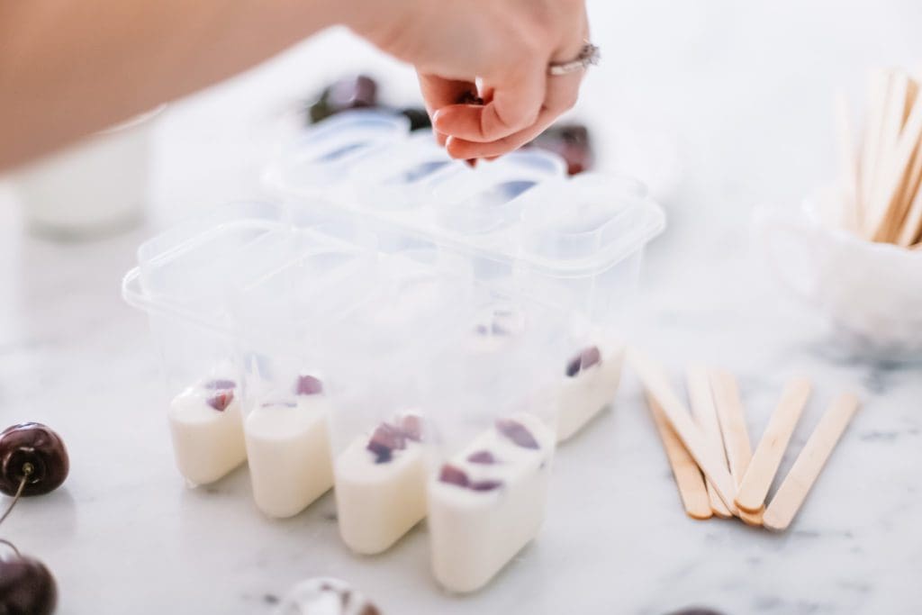 adding cut cherries to popsicle molds