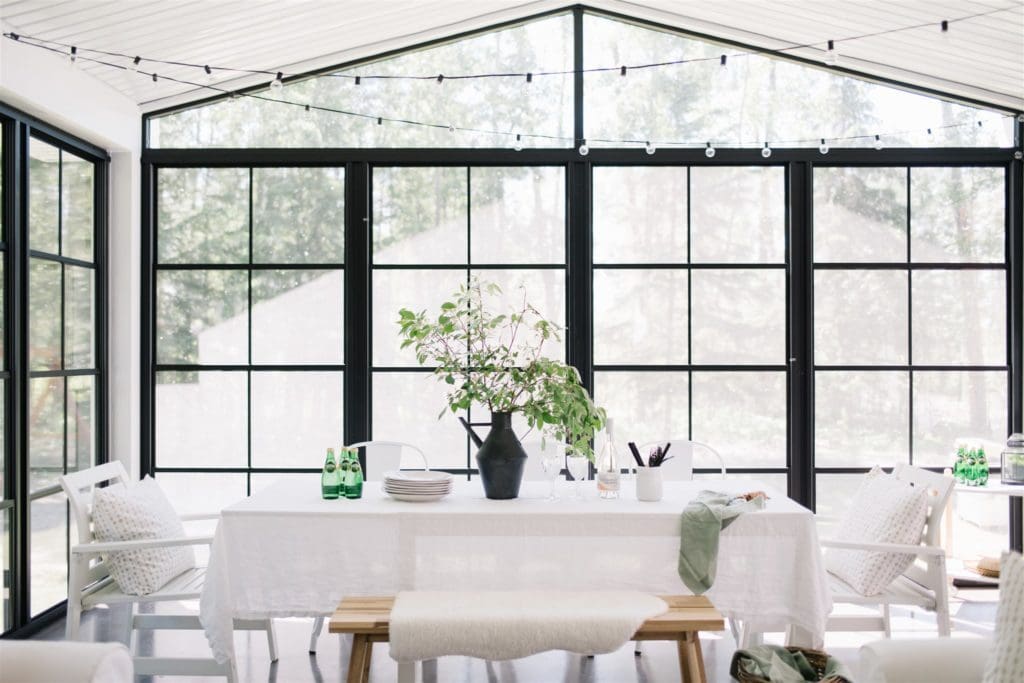 dining room table in an outdoor screen room with patio lights above