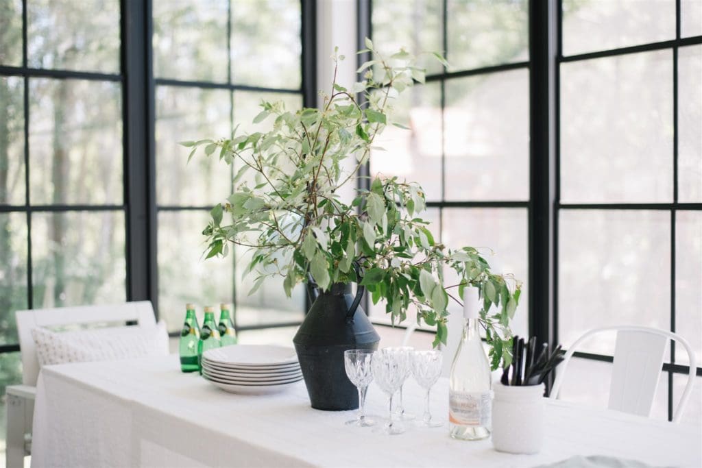 A vase of greenery on a table next to a window