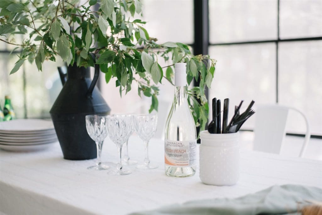 A bottle of white wine and crystal wine glasses sit on a white tablecloth